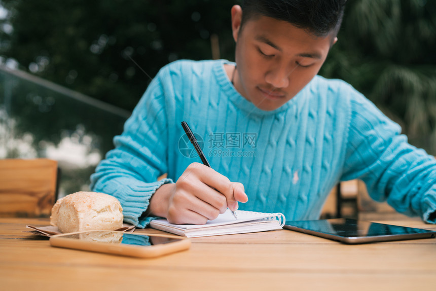 以数字平板电脑和笔记学习的年轻亚洲人肖像图片