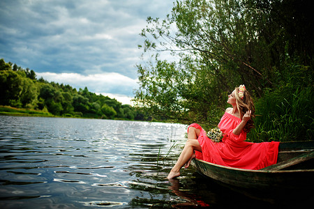 船上放河灯女孩头顶有花圈在河上放轻松和沉睡幻想艺术摄影女美貌的概念自然中休息和水上旅行年轻感女在船上穿红色衣服女孩头上戴花圈在河放松和沉睡背景