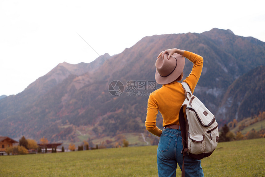 山上草地有背包的姑娘站在山上的草地图片