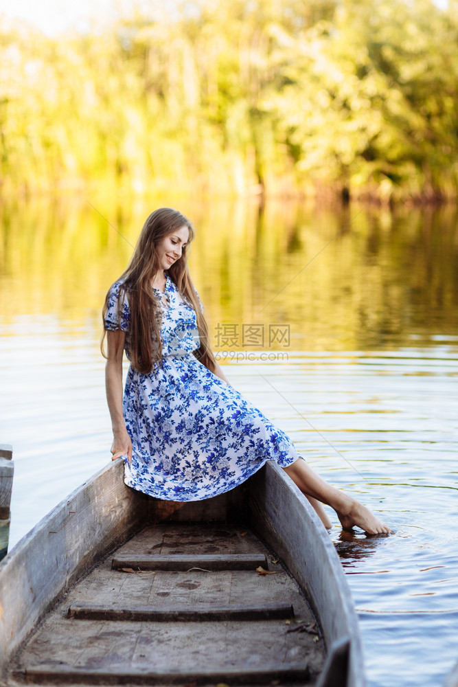 女孩坐在湖里的一条船上玩水图片