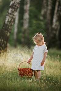 身着白衣带篮子的小女孩在森林中享受阳光灿烂的夏日图片