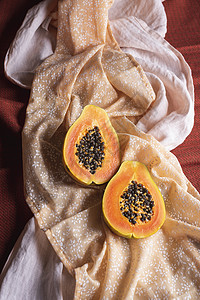 有机木瓜水果切成两半以橙色布料为背景背景图片