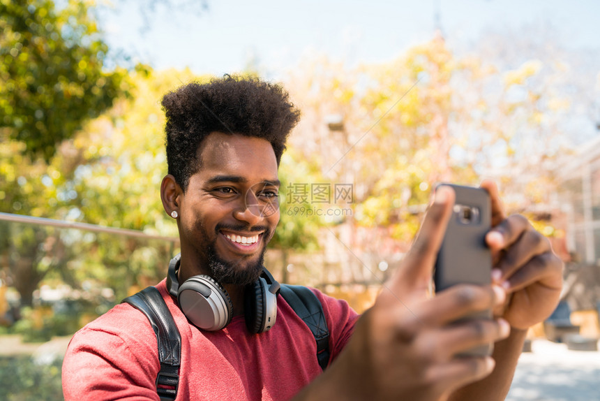 年轻for男人在街上用摩菲手机拍自的肖像技术概念图片