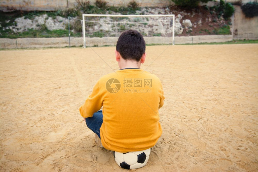 悲伤的男孩在旧足球场等着打图片