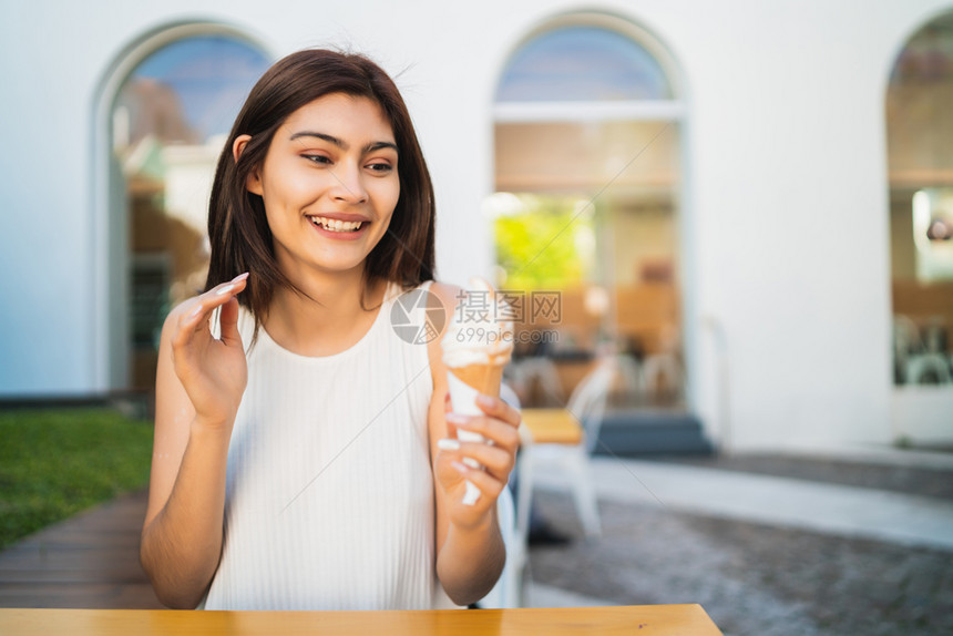 年轻女在户外吃冰淇淋时享受阳光的天气图片