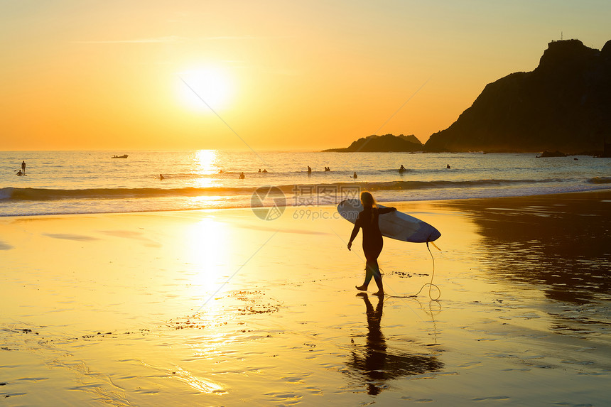 女冲浪者的剪影走到海边的沙滩萨格里斯阿尔加夫葡萄牙图片