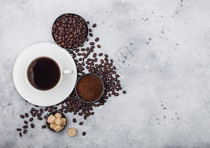 白杯新鲜生有机咖啡豆和地粉甘蔗糖方块咖啡树叶背景浅图片