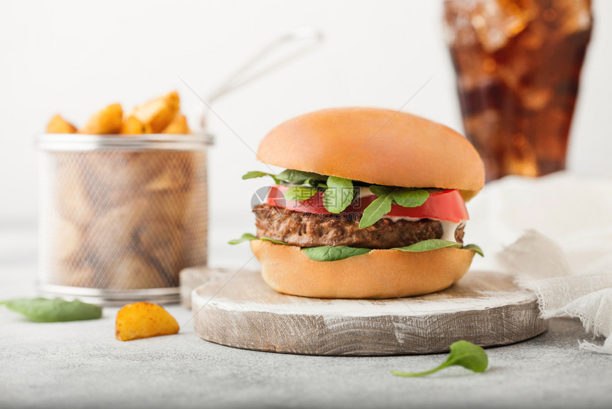 健康素食免费肉汉堡在圆环切肉板上蔬菜在浅底背景土豆杂草和可乐杯图片