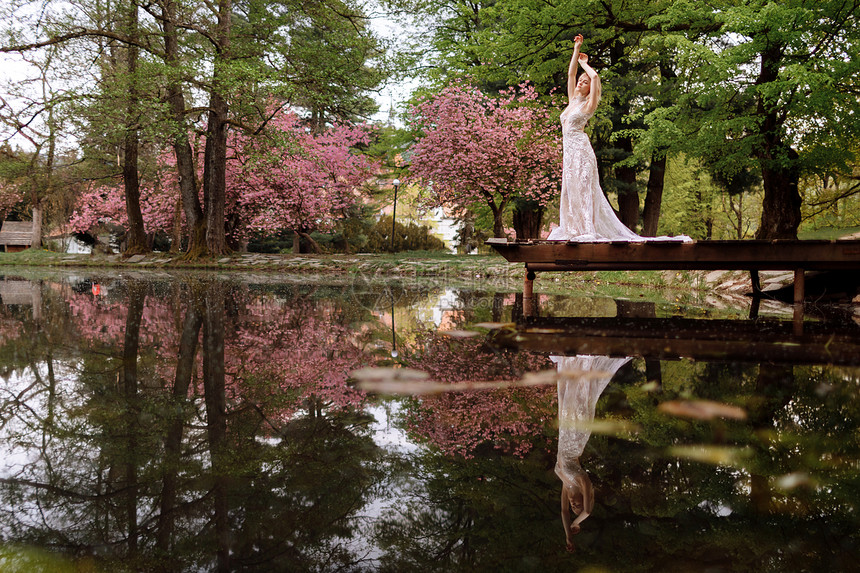 有胡子的年轻男和穿着豪华长装的新娘在湖边公园里拥抱着鲜花和樱桃或婚礼春日有胡子的年轻男和穿着豪华长裙的新娘在湖边公园里拥抱着樱桃图片