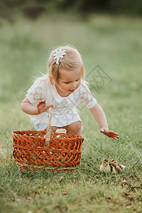 小女孩玩鸭子动物的概念女孩在日落时和可爱的鸭子玩小孩和动物的概念图片