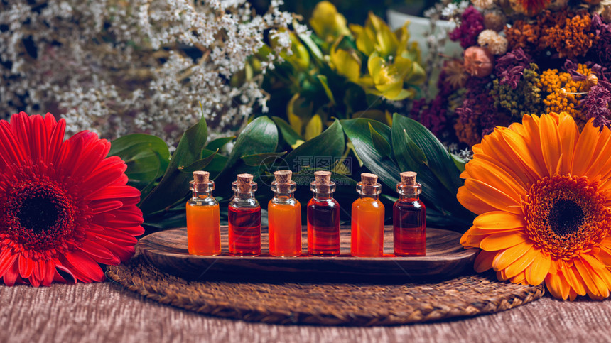 用透明瓶装满木板上的红和橙油花装饰小白背景图片