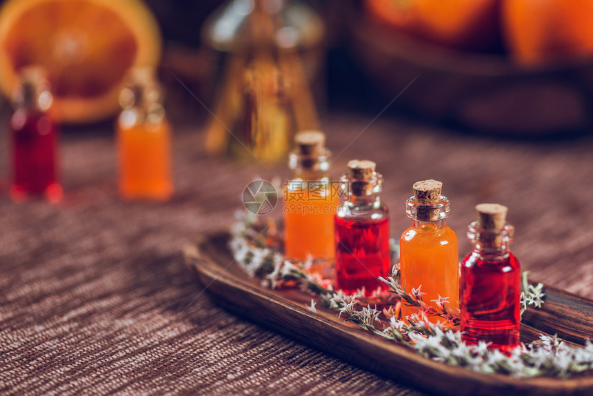 木板上装满红和橙色基本油的瓶子新鲜柑橘水果切成两半图片