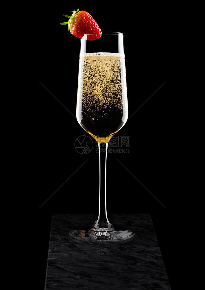 优雅的黄色香槟杯子上面有草莓黑色大理石板上有黑莓图片