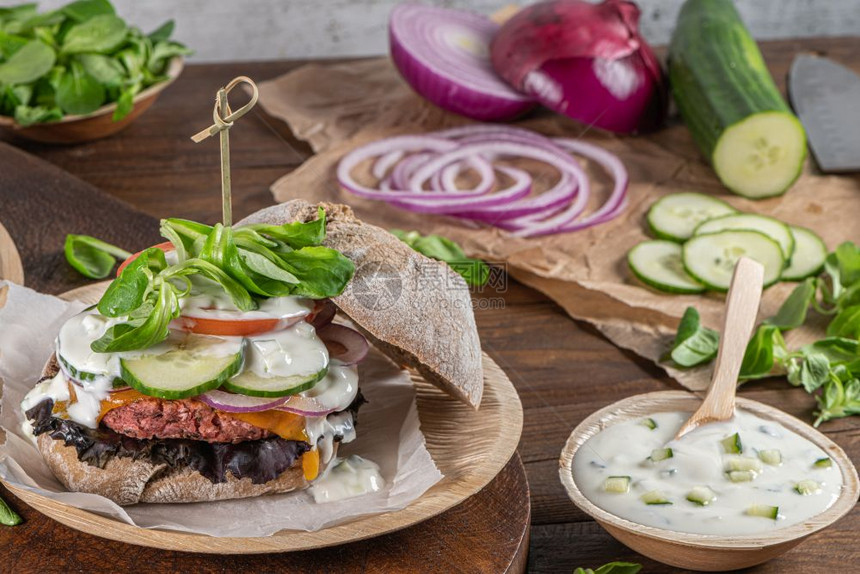 健康的素食汉堡新鲜蔬菜和酸奶酱在生锈的厨房柜台顶端图片