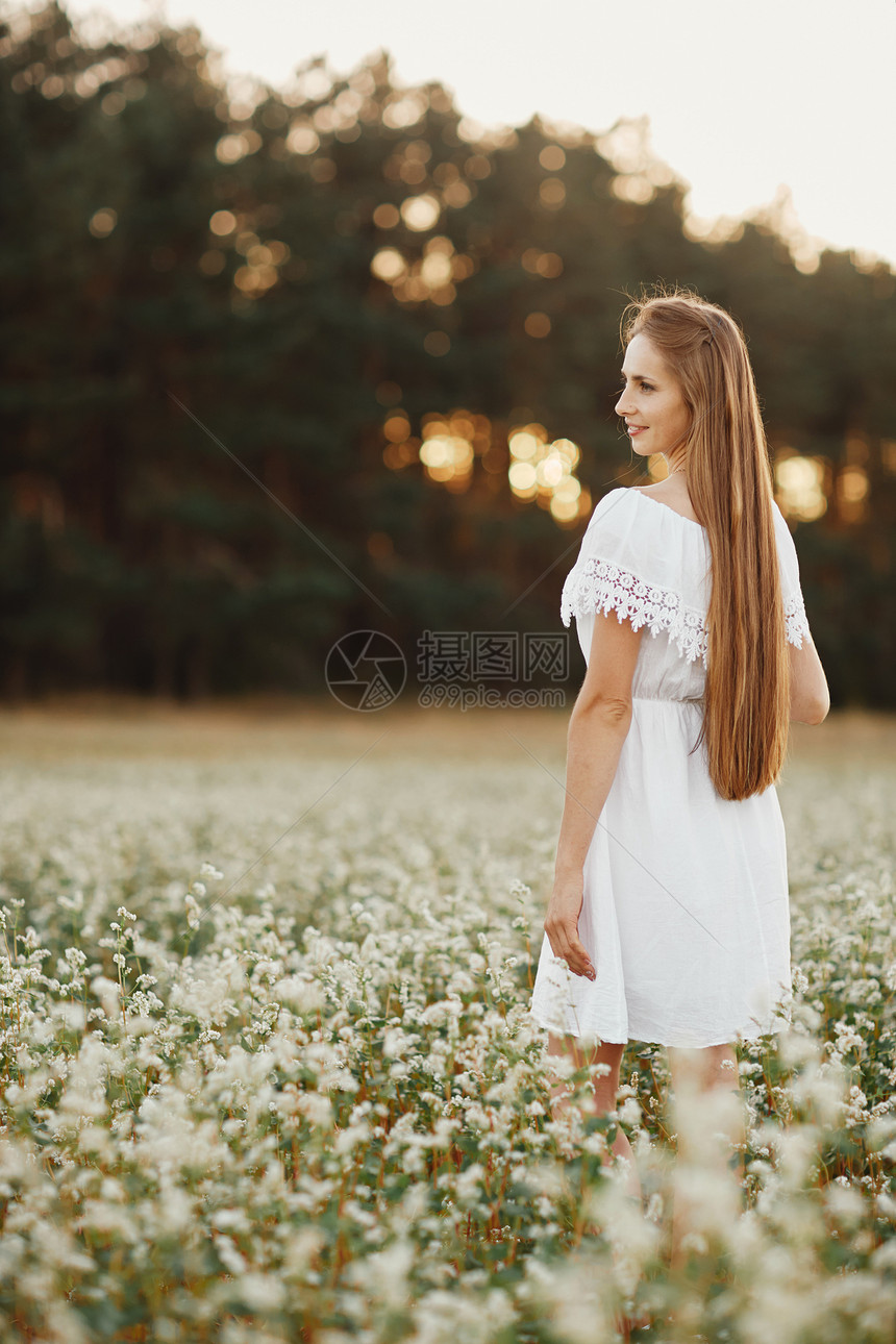 一个美丽的女孩肖像穿着白色的礼服在开花田野里一位美丽的女孩肖像在开花田里朵野夏天与自然的团结图片