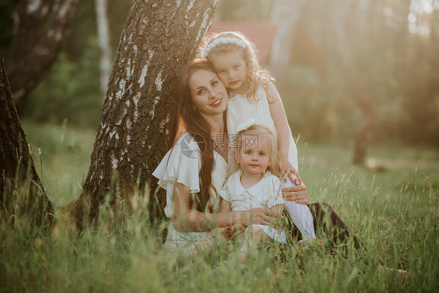快乐的母亲和两个女儿在公园中美丽的自然场景与家庭户外生活方式幸福的家庭一起在绿草地上休息户外快乐幸福和家庭生活的谐与图片