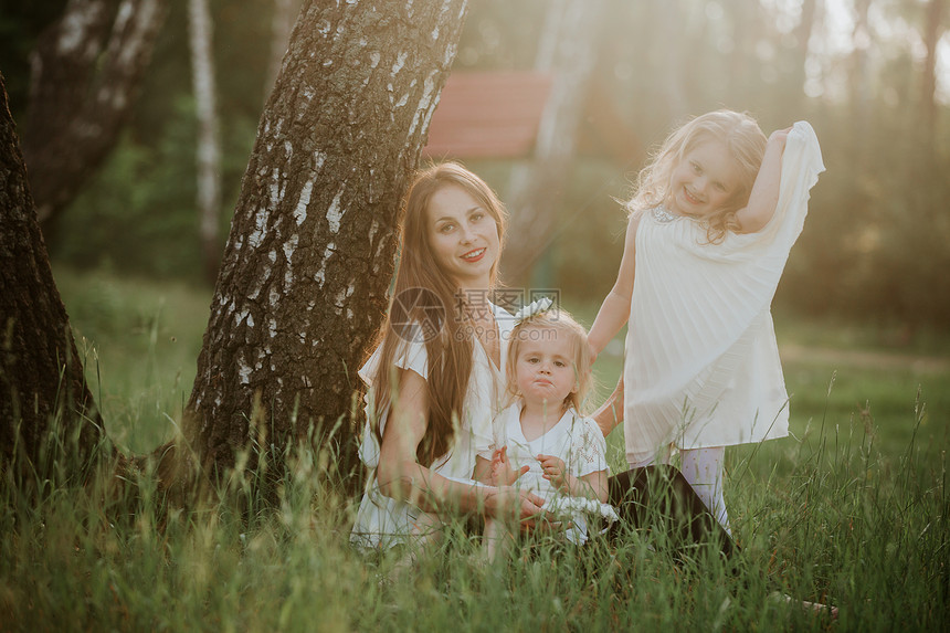 快乐的母亲和两个女儿在公园中美丽的自然场景与家庭户外生活方式幸福的家庭一起在绿草地上休息户外快乐幸福和家庭生活的谐与图片