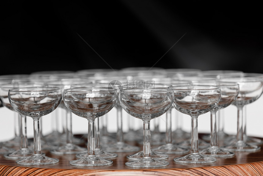 婚礼当天在木制桌边的酒杯或香槟子上有许多优雅的空酒杯或香槟子一套在行内展示的空杯子准备渡假许多优雅的空酒杯或香槟子在婚礼当天的木图片