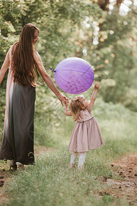 美丽的母亲和女儿在绿色田地里玩得开心图片