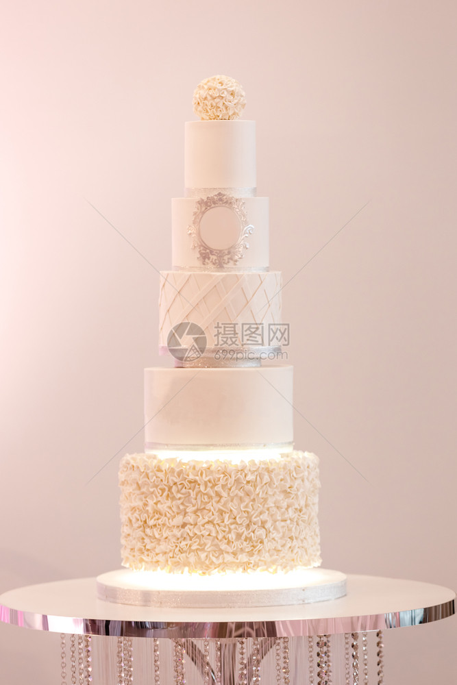 一个白色的大型皇家蛋糕在豪华婚礼上装饰银子细节和白奶油新娘和郎的节庆晚宴后甜点选择焦图片