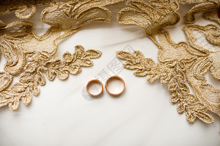 一对金色的结婚戒指戴着蕾丝的面纱结婚附件选择焦点戴着蕾丝的面纱图片