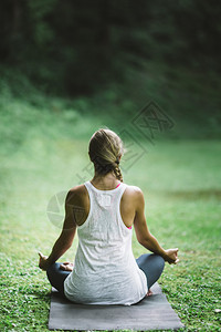 美丽的放松年轻女士做瑜伽坐在半个莲花的姿势图片