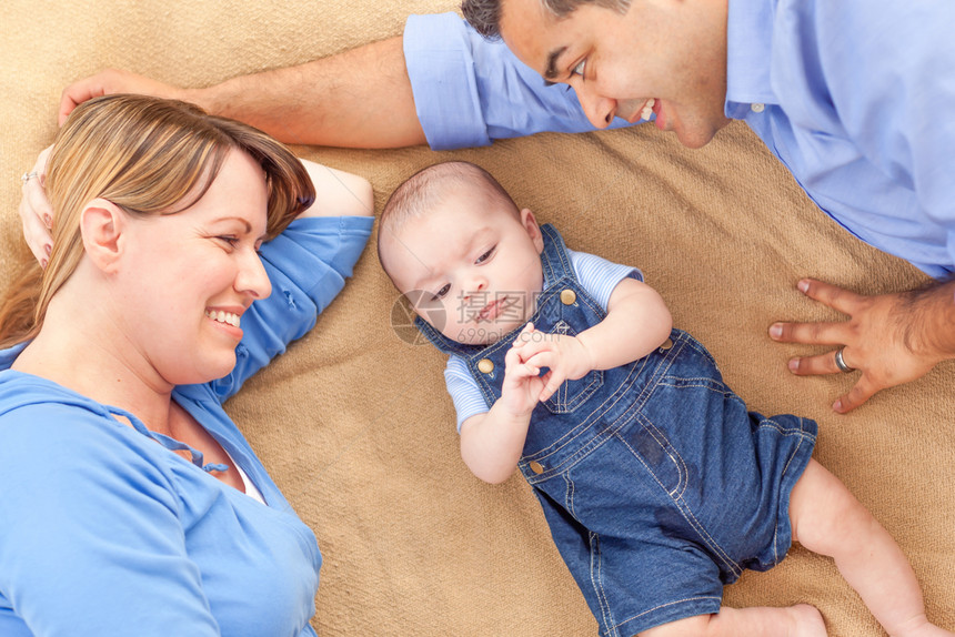 年轻的夫妇带着婴儿躺在毯子上图片