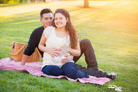 丈夫带孕期妻子在公园草坪上休息图片