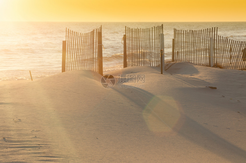 美丽的日落在海面上加沙子的栅栏图片