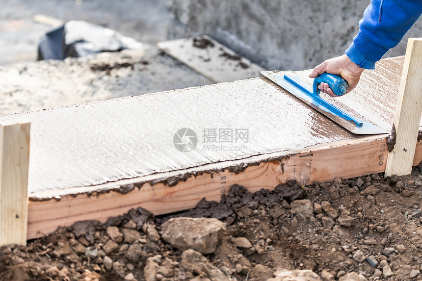 建筑工人在新的游泳池周围利用湿水泥的粗糙土来应对图片