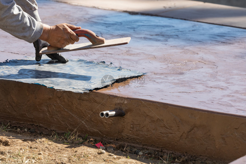 建筑工人对湿水泥上的纹理模板施压图片