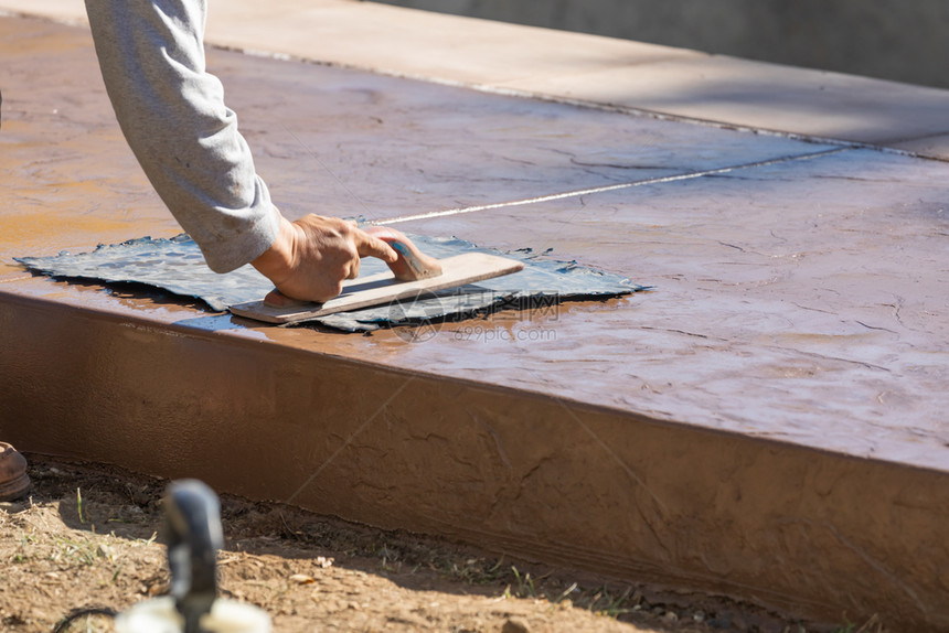 建筑工人对湿水泥上的纹理模板施压图片