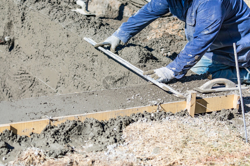 使用滑棒在湿混凝土上工作的建筑池人图片