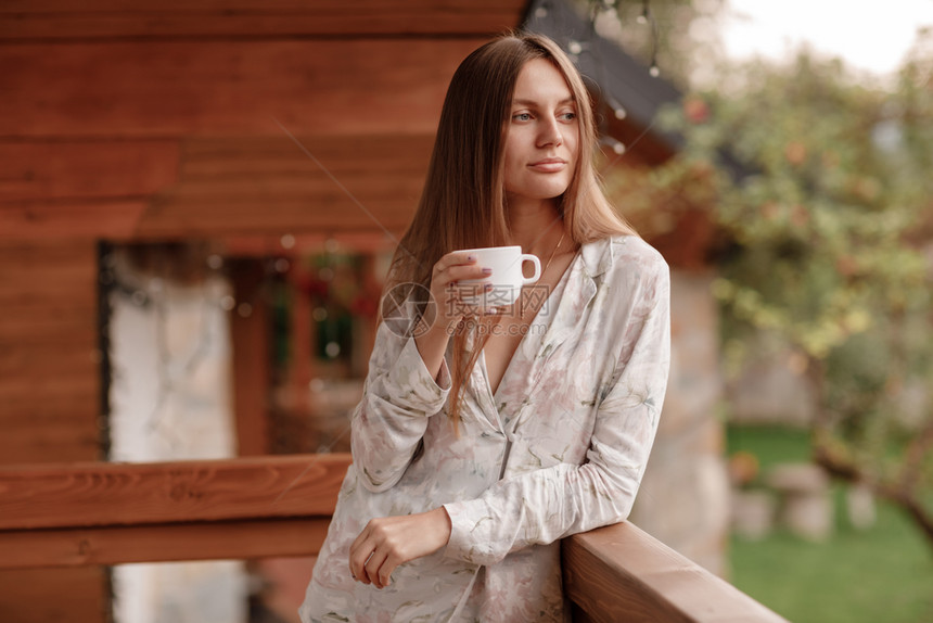 女孩站在阳台喝咖啡的肖像图片