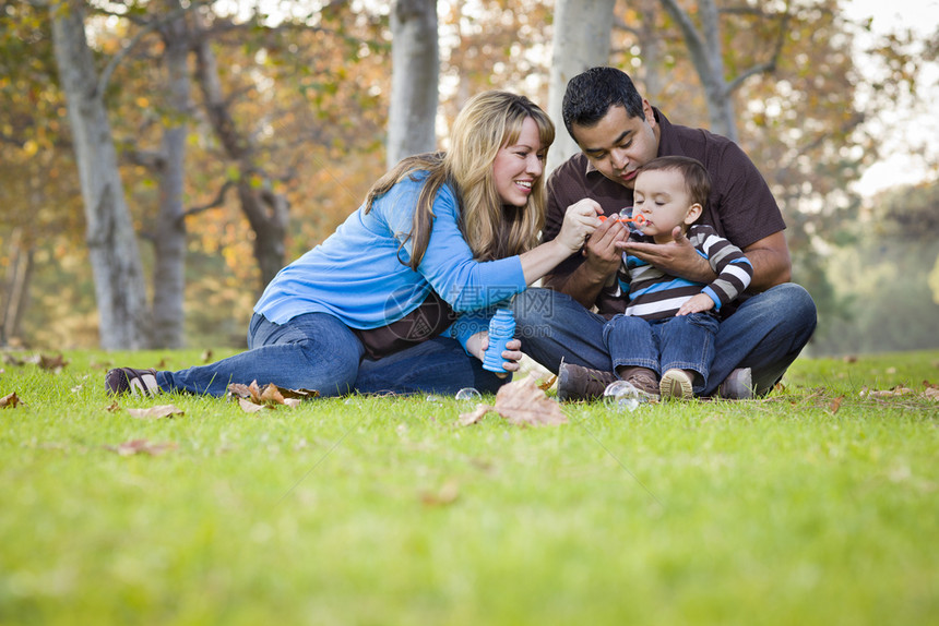 夫妇和儿童坐在草坪上玩泡泡图片