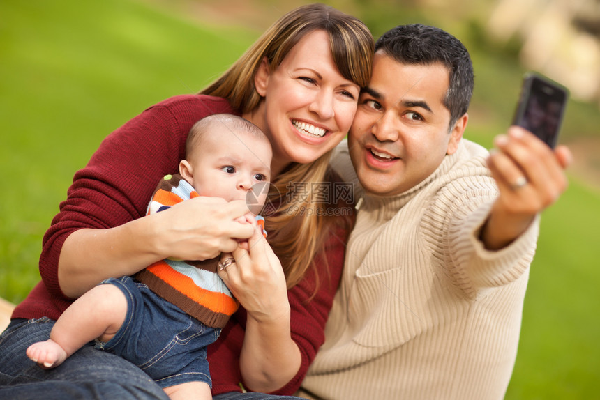 快乐的混合种族父母和婴儿男孩在公园开心的自拍图片