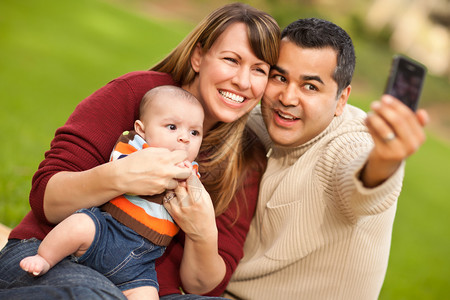 快乐的混合种族父母和婴儿男孩在公园开心的自拍图片