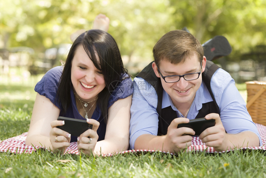 公园里有吸引力的年轻夫妇一起在智能手机上发短信图片