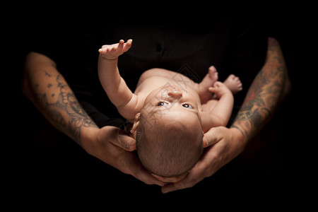 父亲的手将新生婴儿用黑底灯光照亮图片