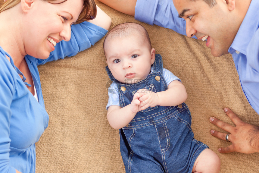 年轻混血夫妇带着婴儿躺在毯子上图片