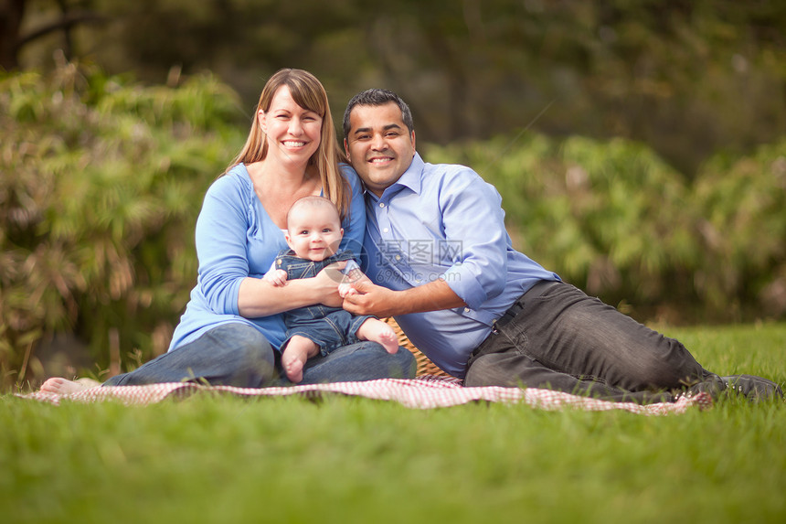 年轻夫妇带婴儿在草坪的地毯上开心的玩耍图片