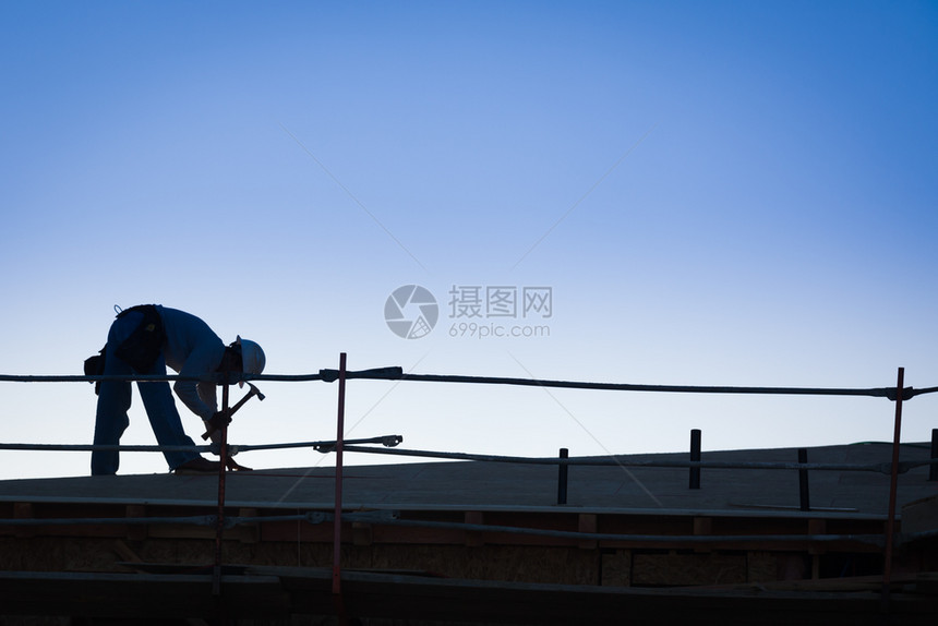 夕阳下建筑工人在屋顶上的背景图片
