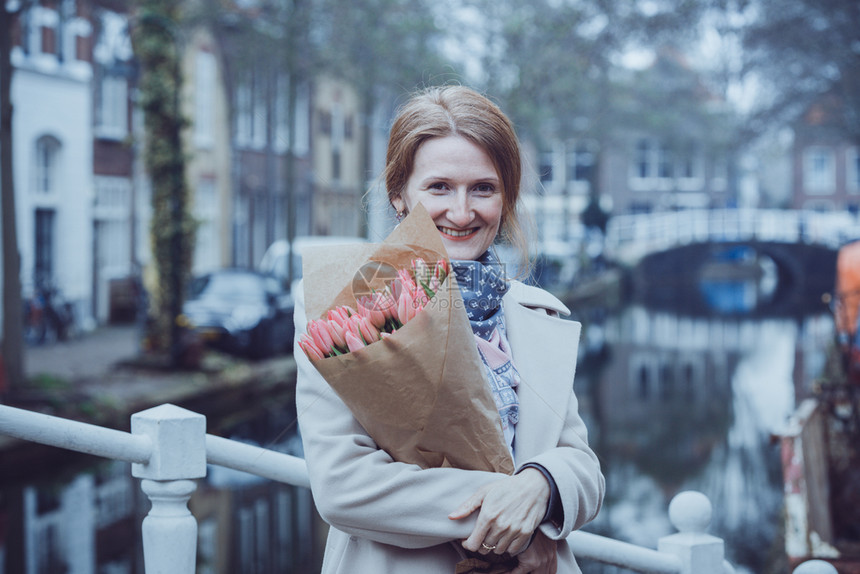 快乐的女孩拿着一束郁金香站在阿姆斯特丹街上图片