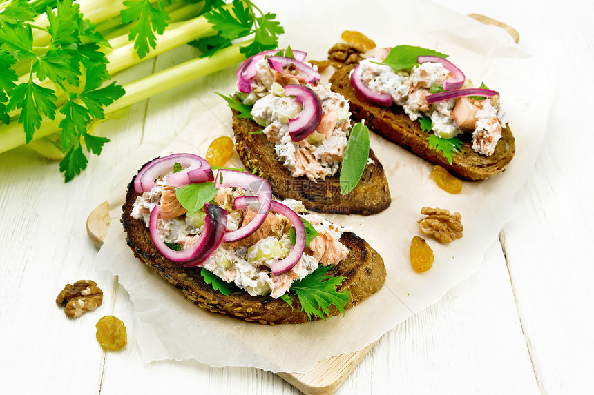 鲑鱼沙拉小茶菜葡萄干胡桃红洋葱和烤面包上干酪奶纸绿色生菜浅木板背景图片
