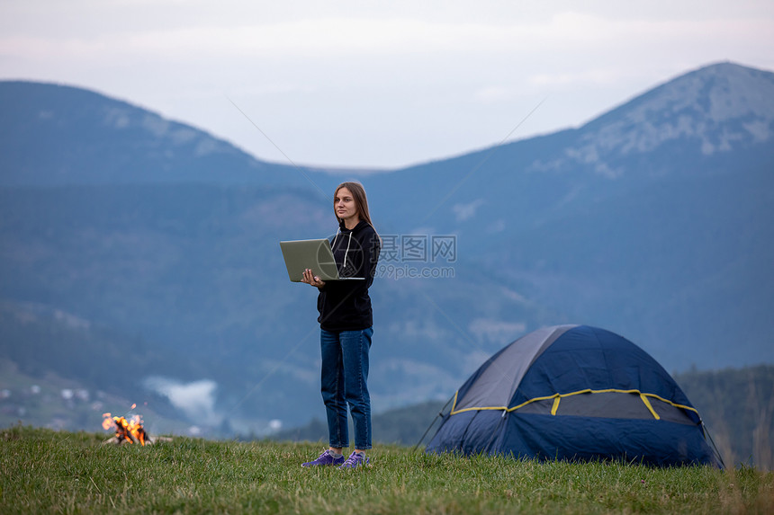 青年女自由职业者晚上在山区用笔记本电脑工作游客女孩坐在营火附近玩得开心复制空间年轻女自由职业者晚上在山区用笔记本电脑工作旅游女孩图片