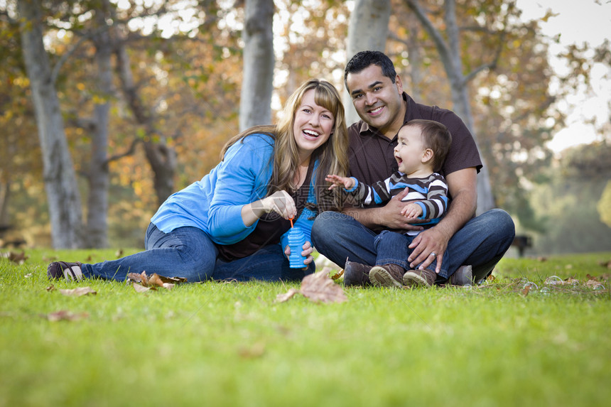 快乐的年轻人混合种族民家庭一起玩与泡沫在公园图片