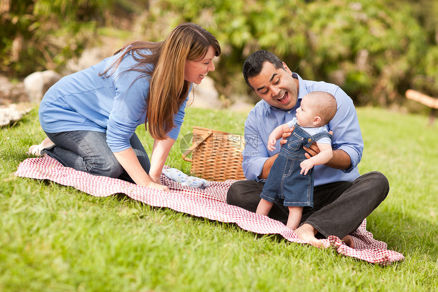 快乐的混合种族家庭在公园野餐玩耍图片