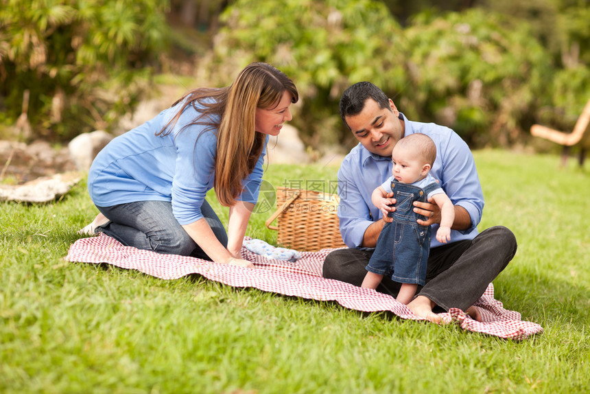 快乐的混合种族家庭野餐和在公园玩耍图片
