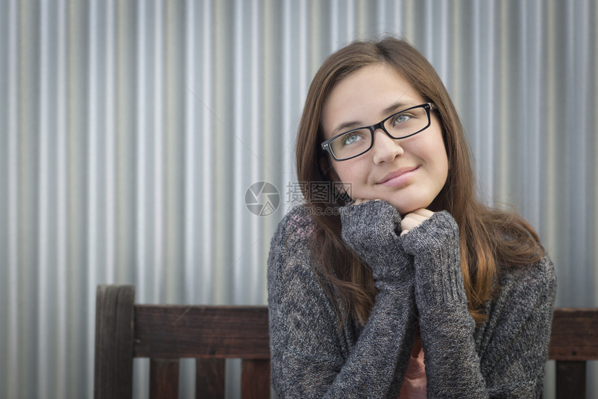 白日梦中的年轻女孩戴着眼镜仰望坐在长椅上的侧面图片