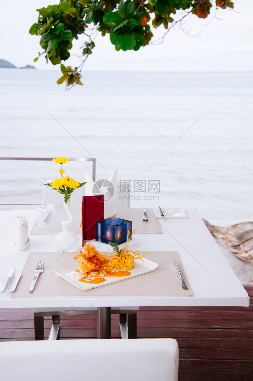 在热带岛屿海边的午餐桌上配有芒果沙拉和一千个岛酱图片
